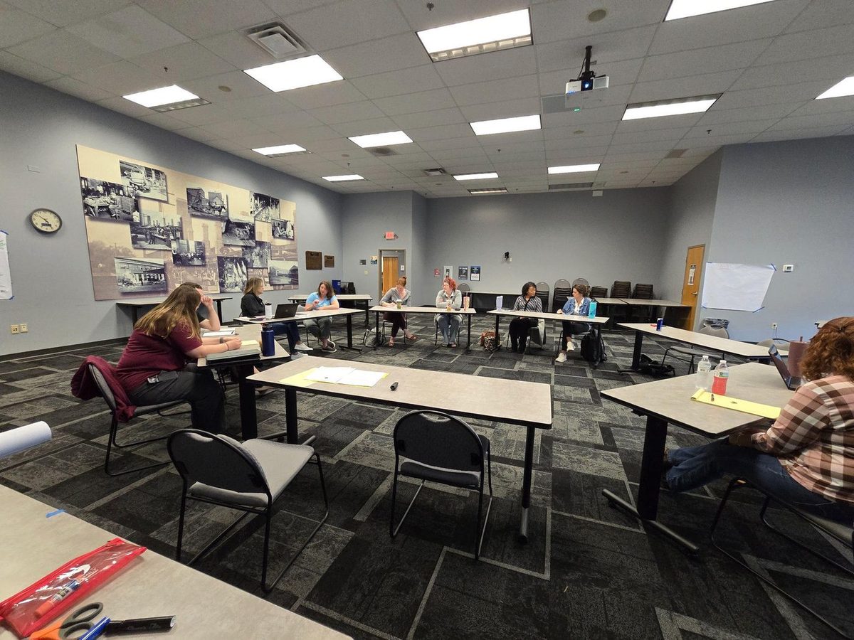 A team in a facilitated Capacity Pause session, seated in an open circle of tables